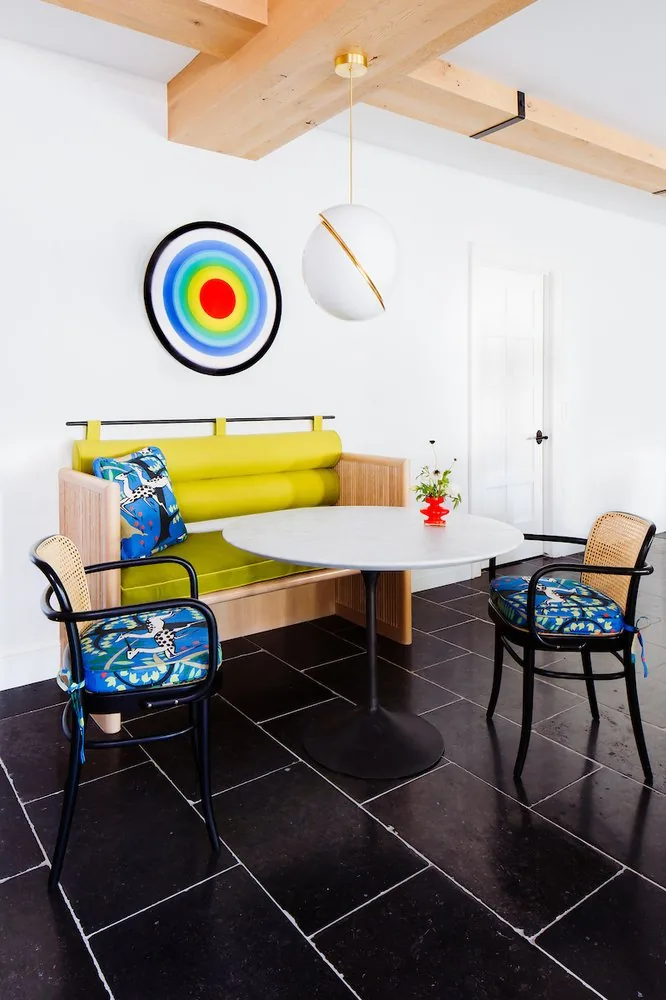 Happy Hollow kitchen banquette, chartreuse upholstered bench, cane bistro chairs with printed cushions, and Saarinen tulip table. Studio Eckström