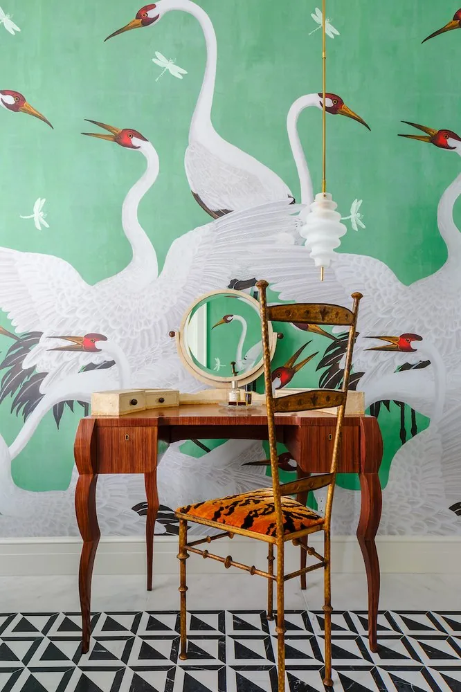Happy Hollow primary bathroom, antique dressing table with round mirror, gilt Chiavari chair in tiger velvet, and crane mural on emerald ground. Studio Eckström