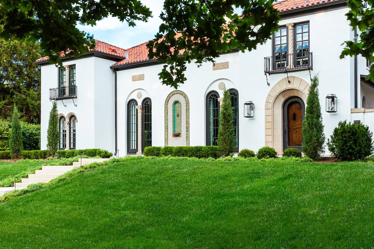 Happy Hollow exterior, Spanish Colonial Revival with arched windows, terracotta tile roof, iron balconies, and manicured grounds. Studio Eckström