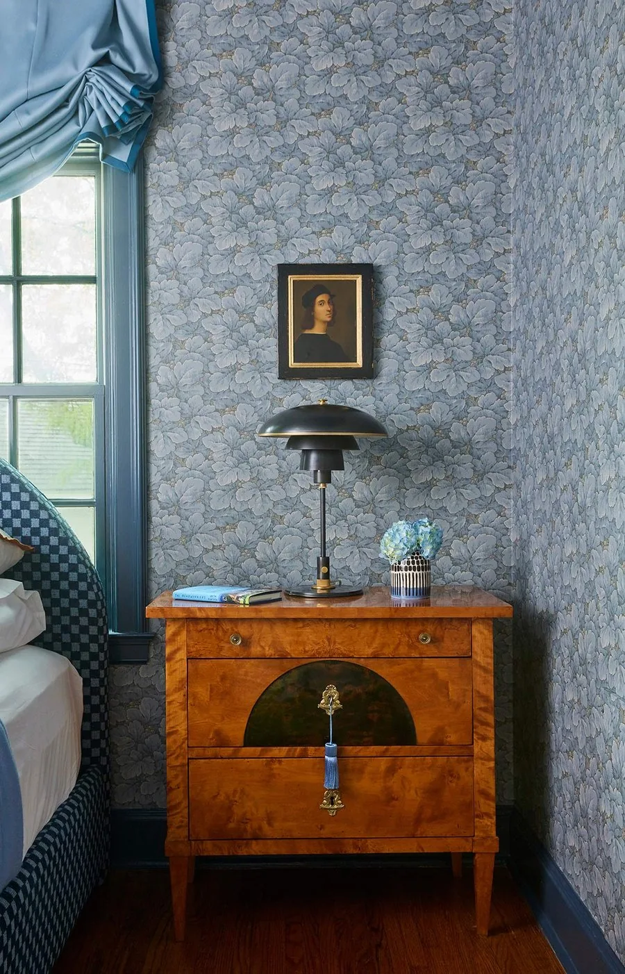 The Swedish Homage, burl walnut Biedermeier nightstand with PH lamp, antique oil portrait, and blue floral wallpaper. The Dundee Remodel, Studio Eckström Omaha
