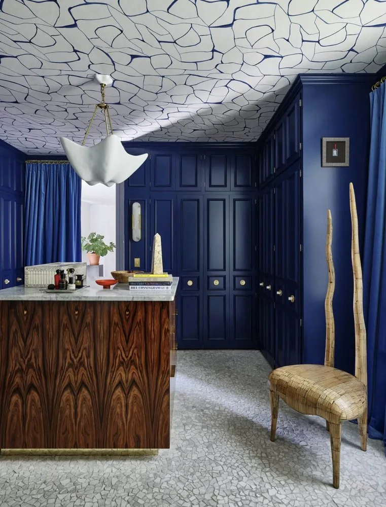 The Architectural Digest Townhome dressing room, deep navy wall-to-wall cabinetry with brass hardware, macassar island with marble top, and pebble terrazzo floor. Studio Eckström 2023