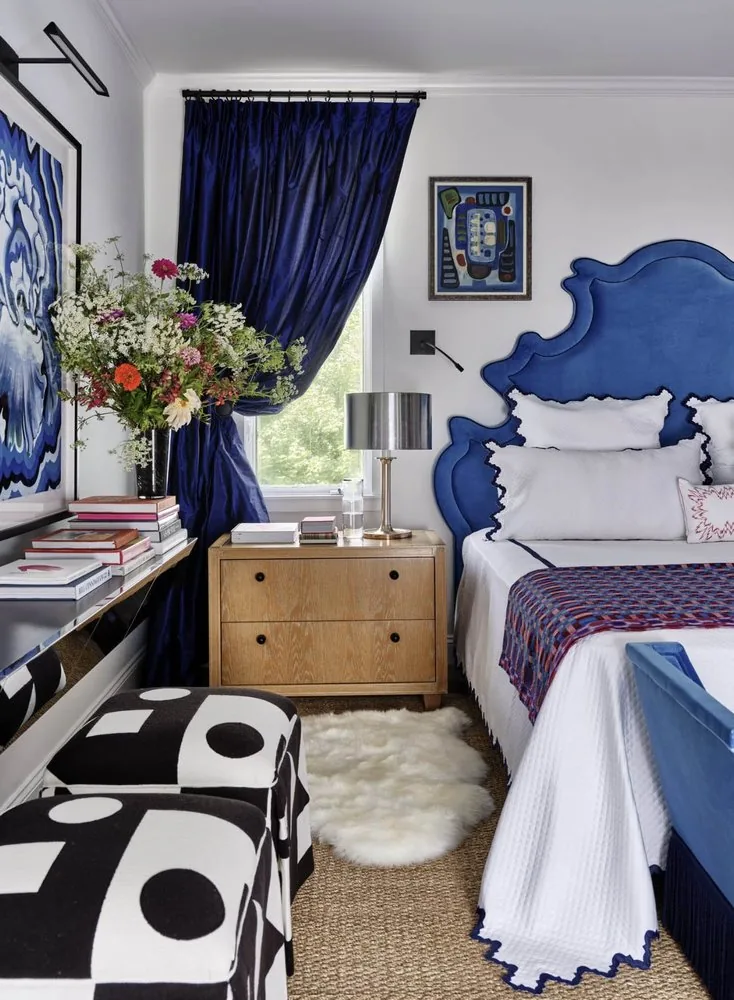 The Architectural Digest Townhome primary bedroom alternate view, cobalt baroque headboard, oak nightstand with chrome lamp, and blue silk curtains. Studio Eckström 2023